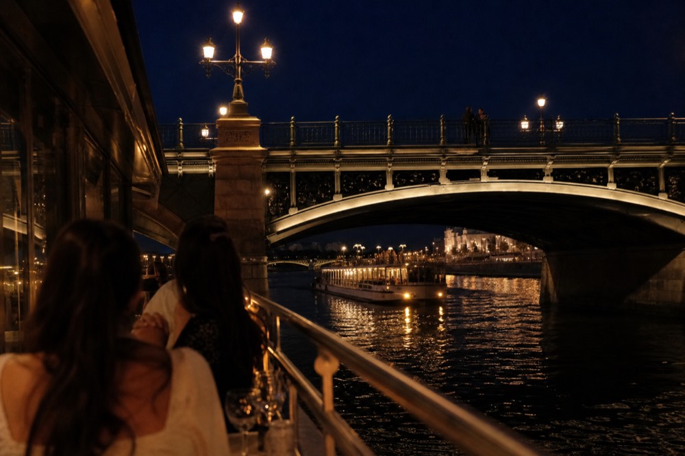 Dinner cruise boat lit at evening passing a Paris bridge, no text, no logos, no people