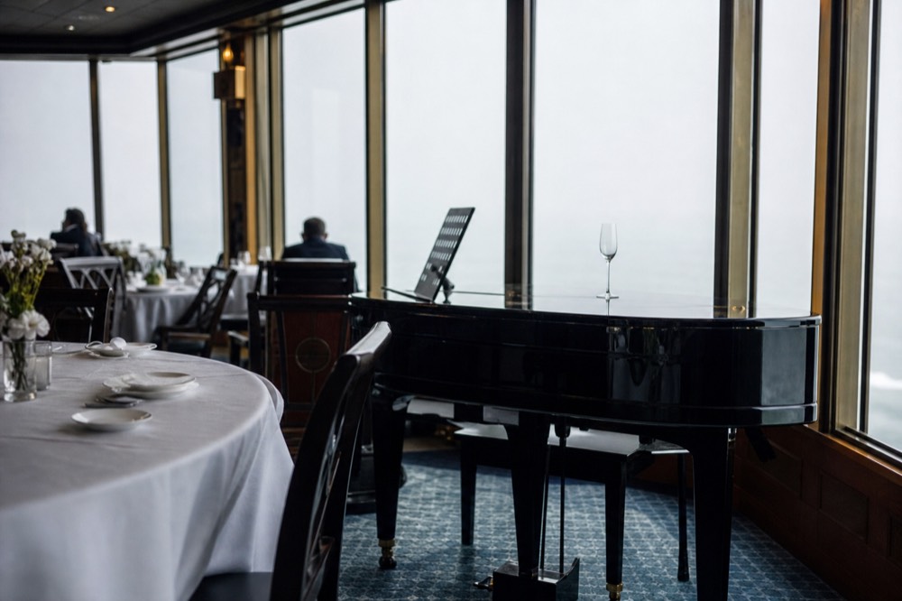 Bateaux Parisiens panoramic glass boat interior with white tablecloths and a baby grand piano, no text, no logos, no people