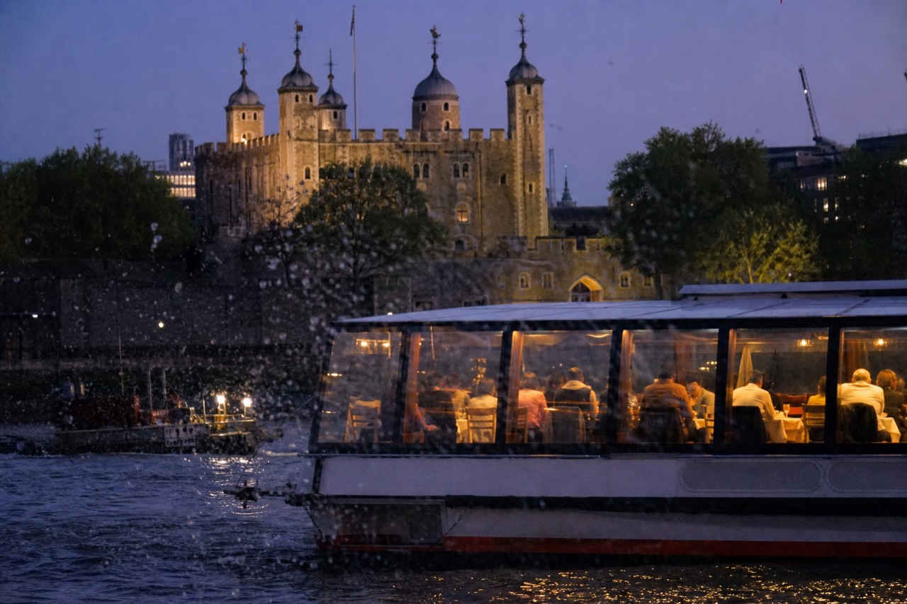 Illuminated dinner cruise boat passing the Eiffel Tower on the Seine at dusk, no text, no logos, no people