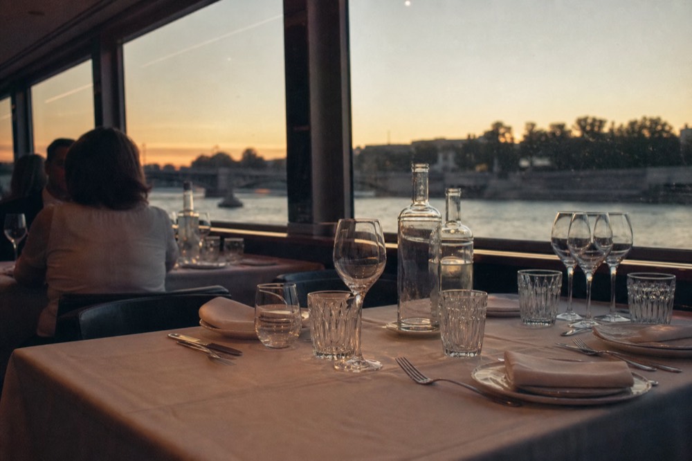 Elegant dinner table set with glassware aboard a Seine cruise boat, no text, no logos, no people
