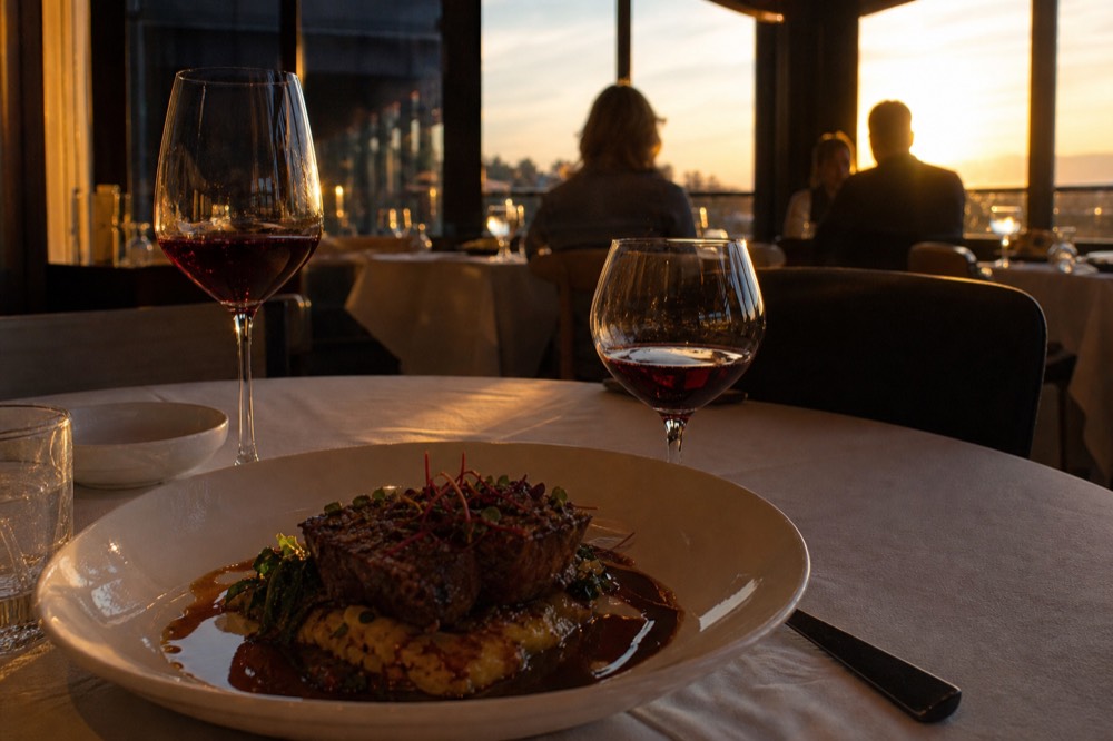 Wine glasses and a plated gourmet course on a dinner cruise table, no text, no logos, no people