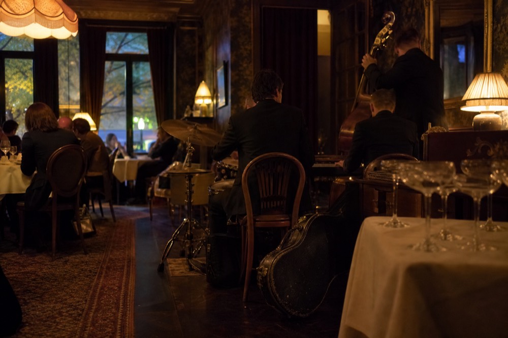 A vintage-styled dining room with warm lamps and jazz musicians, no text, no logos, no people