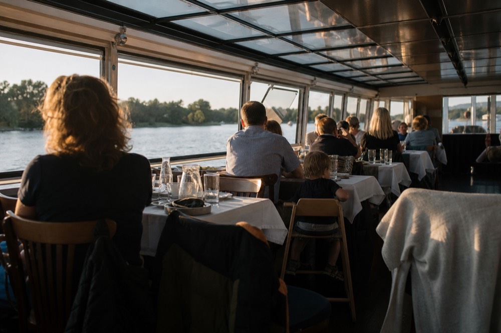A family table set for dinner aboard a covered Seine cruise boat, no text, no logos, no people