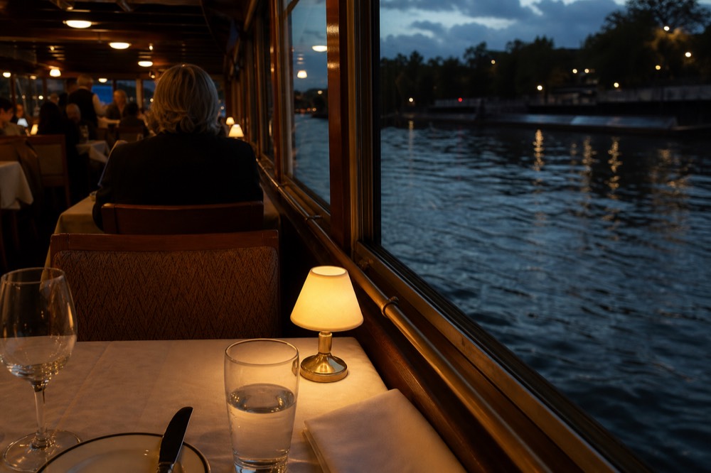 Seine dinner cruise table with glass and river view, no text, no logos, no people