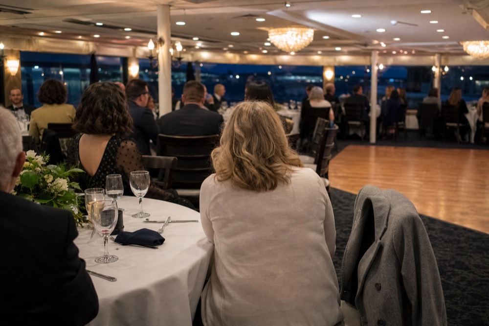 Guests in smart-casual evening wear seated at round tables on a dinner cruise dancefloor, no text, no logos, no people