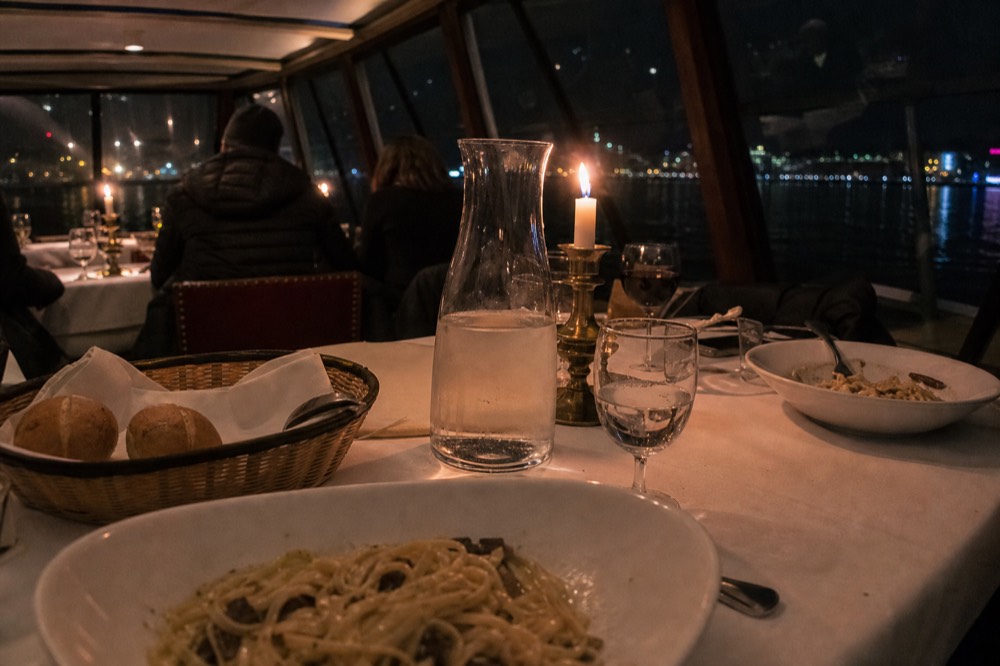 A candlelit dinner table with pasta dishes set aboard a boat, no text, no logos, no people