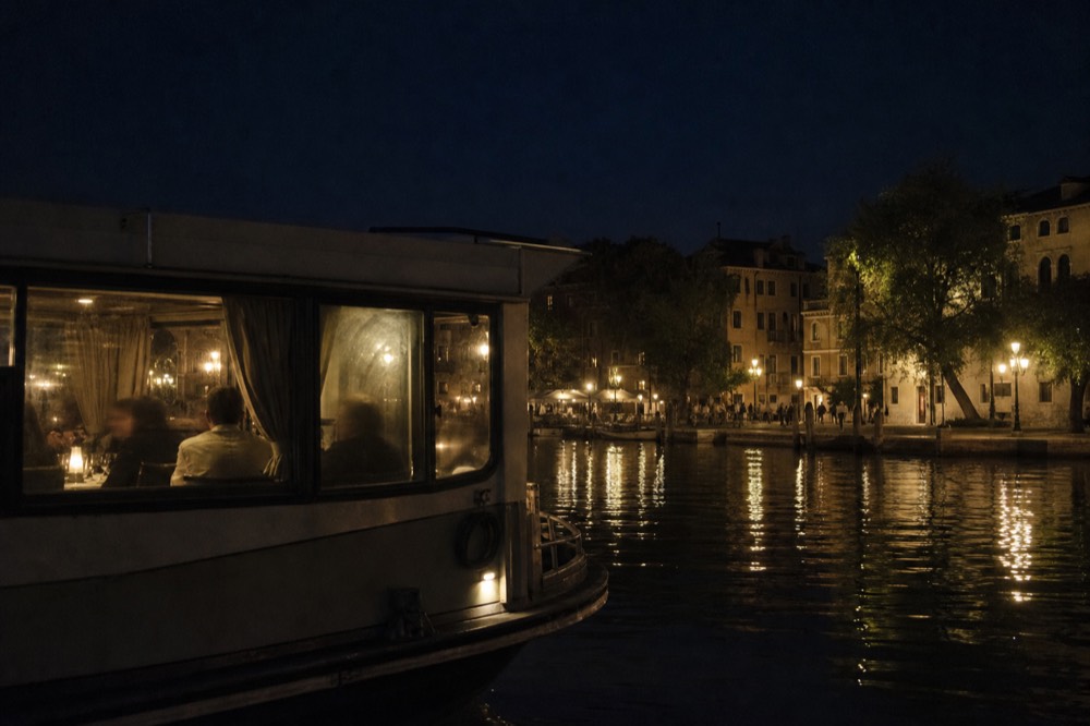 A dinner cruise boat passing illuminated Paris bridges at night, no text, no logos, no people.