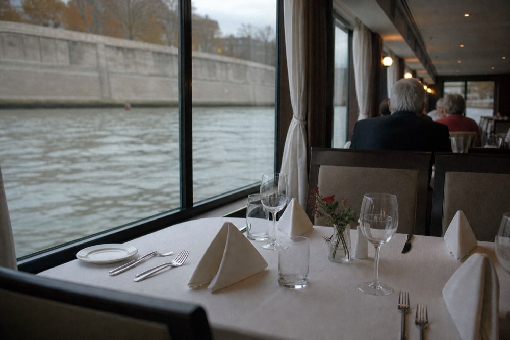 Elegantly set dinner table on a Paris river cruise boat, no text, no logos, no people